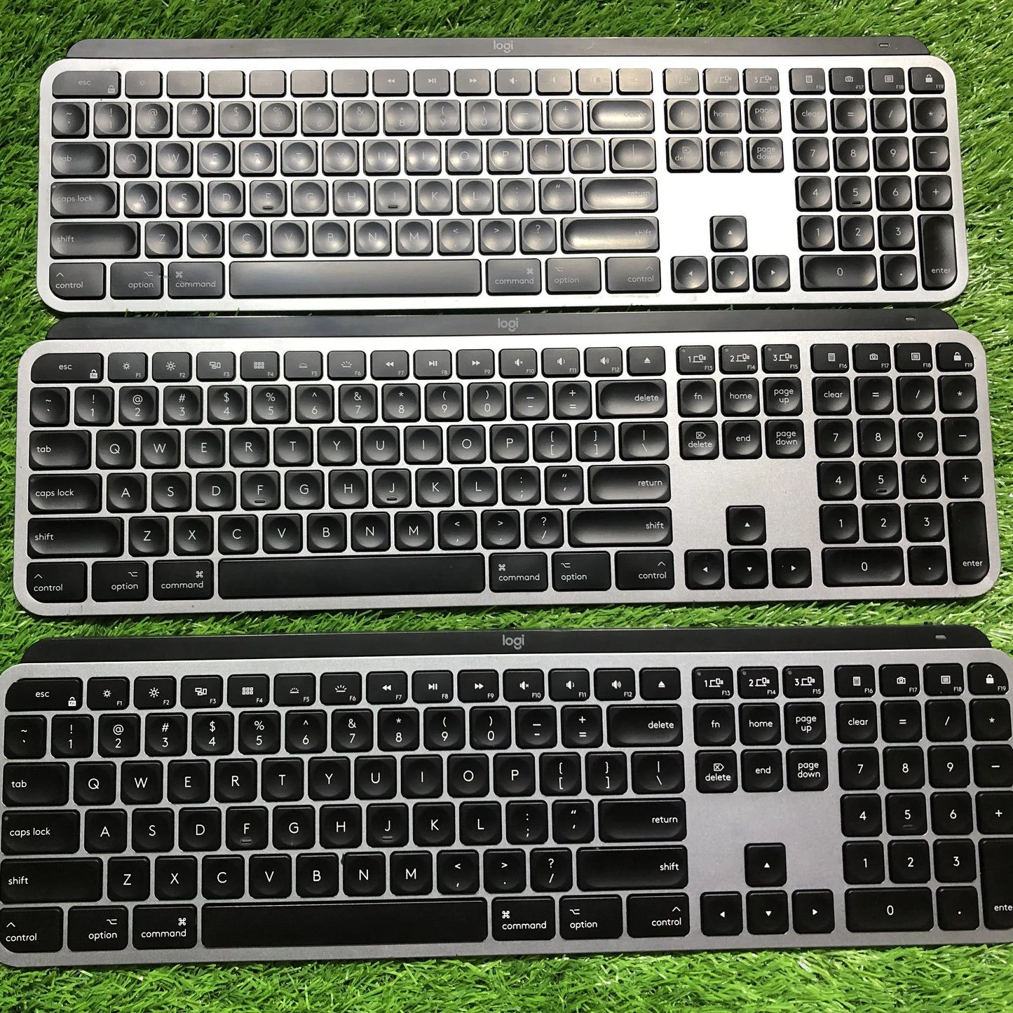 Three keyboards of different designs on a grassy background