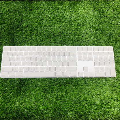 White keyboard on green grass with a brown surface above